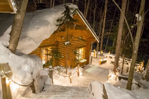 在黄昏被雪包围发光的小木屋 — 图库照片