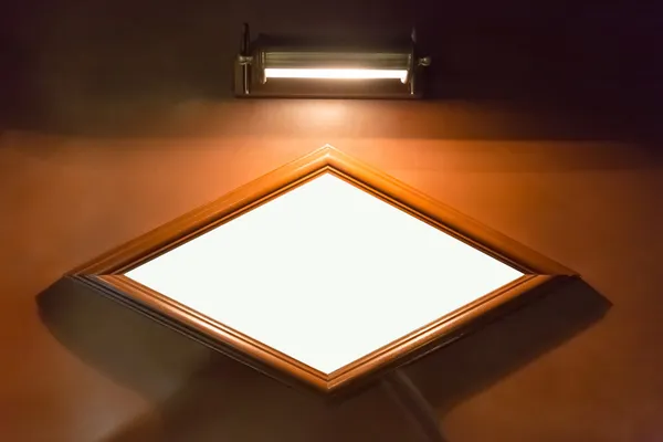 Quadro de avisos em forma de diamante em branco na parede com iluminação — Fotografia de Stock