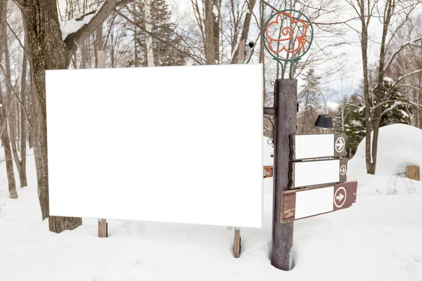 Cartelera en blanco y señal de dirección en la nieve — Foto de Stock
