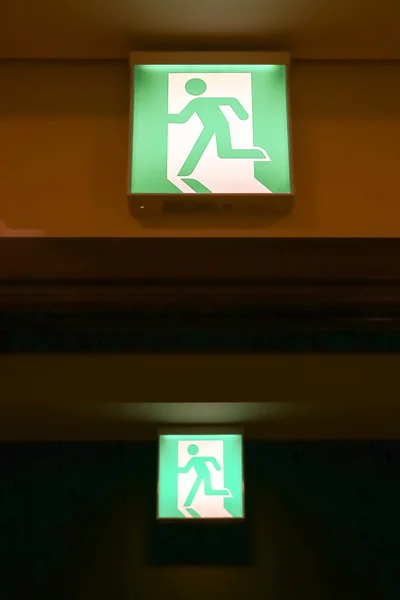Zielony znak wyjścia awaryjnego wskazujący drogę ucieczki — Zdjęcie stockowe