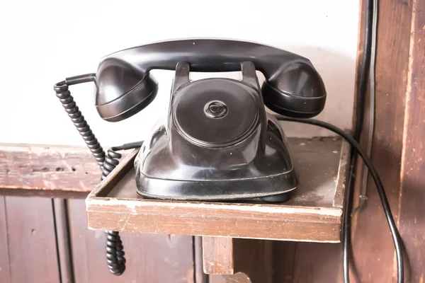 Винтажный черный телефон на фоне старого деревянного стола — стоковое фото