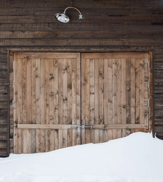 Gamla ladugården trädörr med ljus och snö — Stockfoto