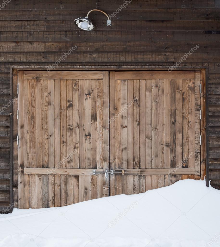 Old wooden barn door with light and snow