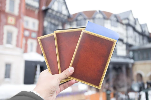 Mano humana sosteniendo libros vacíos y boleto — Foto de Stock