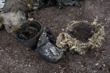 Yerde yanmış askeri miğferler var.