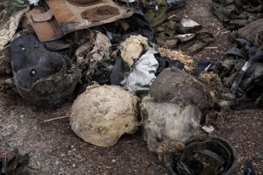 Yerde yanmış askeri miğferler var.