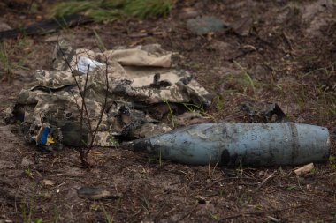 Yanmış askeri üniforma, ayakkabılar, topçu mermisi.