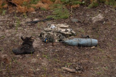 Burnt military uniform, shoes, artillery shell