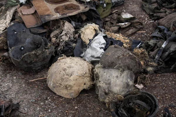 Yerde yanmış askeri miğferler var.
