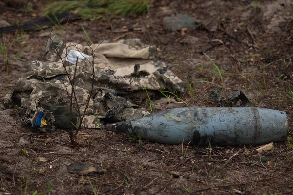 Yanmış askeri üniforma, ayakkabılar, topçu mermisi.