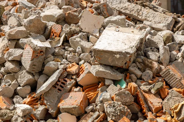 A pile of broken red bricks and fragments of concrete - a destroyed building. Broken bricks close up. Demolition or destruction of buildings. Construction debris.
