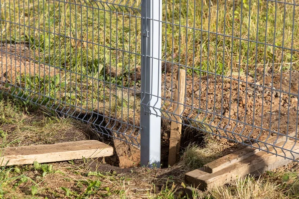 Installation of a metal fence. The process of installing support poles. Pit in the ground.