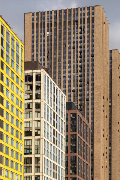 Rows of windows in residential skyscrapers. Dense rows of modern high-rise residential buildings. The problems of urban overpopulation. Residential skyscrapers. Vertical photo.