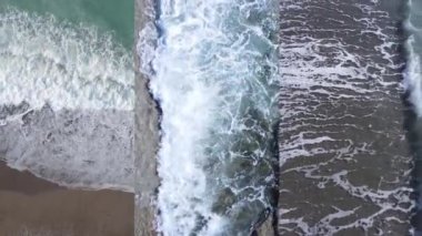 Deniz kıyısının yakınındaki deniz suyunun dikey bir videosunda üç kişi, yavaş çekim.
