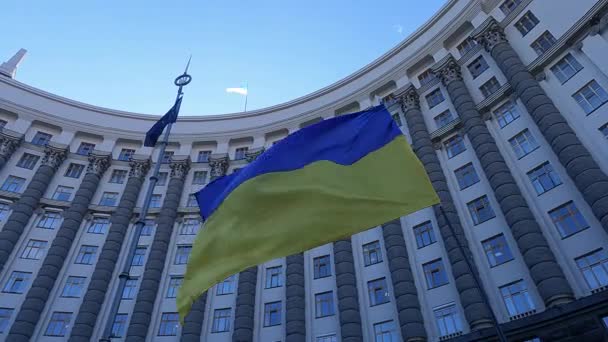 Ukrainas nationella flagga mot bakgrund av regeringsbyggnaden i Kiev — Stockvideo
