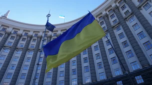 Ukrainas nationella flagga mot bakgrund av regeringsbyggnaden i Kiev — Stockvideo