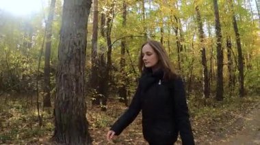 Kız sonbahar ormanında yürüyor.