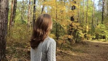 Kız sonbahar ormanında yürüyor.