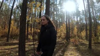 Kız sonbahar ormanında yürüyor.