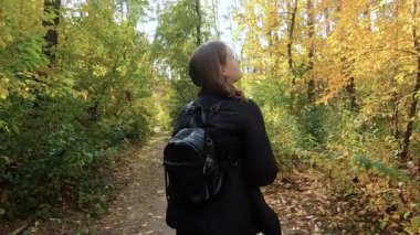 Kız sonbahar ormanında yürüyor.