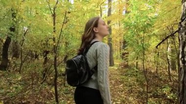 Kız sonbahar ormanında yürüyor.