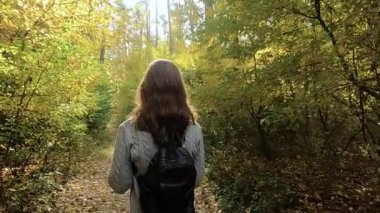 Kız sonbahar ormanında yürüyor.