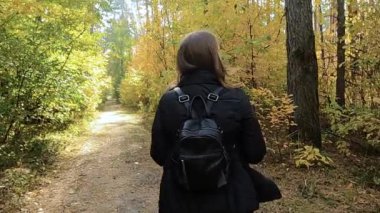 Kız sonbahar ormanında yürüyor.