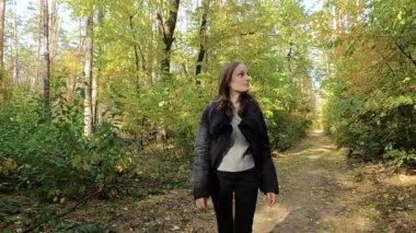 Kız sonbahar ormanında yürüyor.
