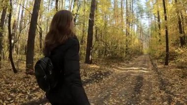 Kız sonbahar ormanında yürüyor.