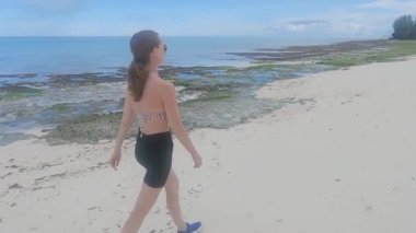 Tanzanya, Zanzibar 'da sahilde yürüyen bir kadın.