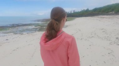 Zanzibar, Tanzanya 'da kumsalda yürüyen bir kadın, ağır çekim.