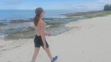 Zanzibar, Tanzanya 'da kumsalda yürüyen bir kadın, ağır çekim.