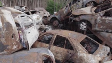 Bu video Irpin, Bucha bölgesinde, gri, düz, renksiz, yanmış arabaları gösteriyor.