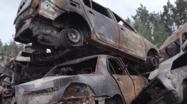 Bu video Irpin, Bucha bölgesinde, gri, düz, renksiz, yanmış arabaları gösteriyor.