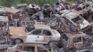 Bu video Irpin, Bucha bölgesinde, gri, düz, renksiz, yanmış arabaları gösteriyor.