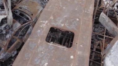 Bu video Irpin, Bucha bölgesinde, gri, düz, renksiz, yanmış arabaları gösteriyor.