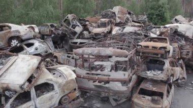 Bu video Irpin, Bucha bölgesinde, gri, düz, renksiz, yanmış arabaları gösteriyor.