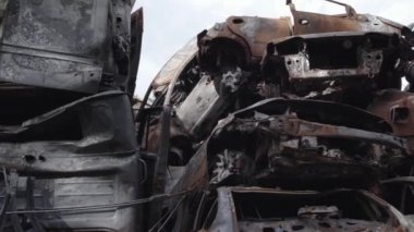 Bu video Irpin, Bucha bölgesinde, gri, düz, renksiz, yanmış arabaları gösteriyor.