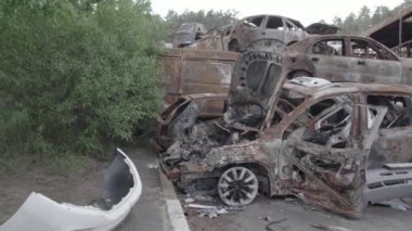 Bu video Irpin, Bucha bölgesinde, gri, düz, renksiz, yanmış arabaları gösteriyor.