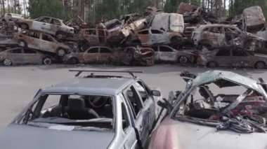 Bu video Irpin, Bucha bölgesinde, gri, düz, renksiz, yanmış arabaları gösteriyor.