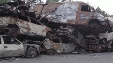 Bu video Irpin, Bucha bölgesinde, gri, düz, renksiz, yanmış arabaları gösteriyor.