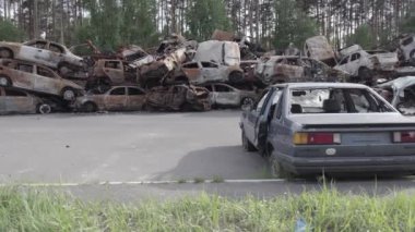 Bu video Irpin, Bucha bölgesinde, gri, düz, renksiz, yanmış arabaları gösteriyor.