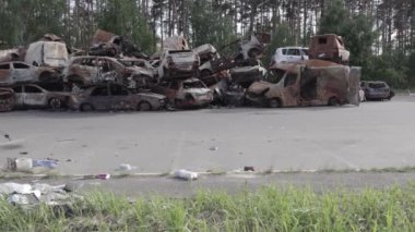 Bu video Irpin, Bucha bölgesinde, gri, düz, renksiz, yanmış arabaları gösteriyor.