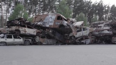 Bu video Irpin, Bucha bölgesinde, gri, düz, renksiz, yanmış arabaları gösteriyor.