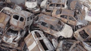 Bu video Irpin, Bucha bölgesinde, gri, düz, renksiz, yanmış arabaları gösteriyor.