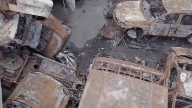 Bu video Irpin, Bucha bölgesinde, gri, düz, renksiz, yanmış arabaları gösteriyor.
