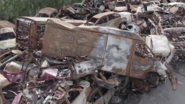 Bu video Irpin, Bucha bölgesinde, gri, düz, renksiz, yanmış arabaları gösteriyor.