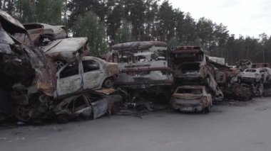 Bu video Irpin, Bucha bölgesinde, gri, düz, renksiz, yanmış arabaları gösteriyor.