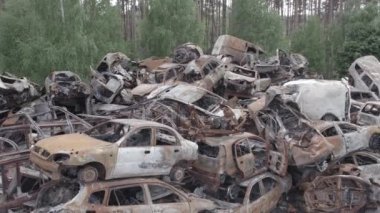 Bu video Irpin, Bucha bölgesinde, gri, düz, renksiz, yanmış arabaları gösteriyor.