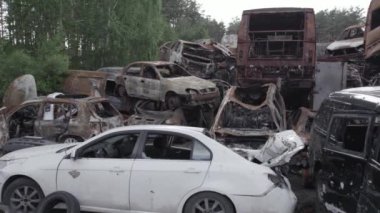 Bu video Irpin, Bucha bölgesinde, gri, düz, renksiz, yanmış arabaları gösteriyor.